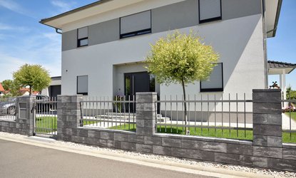 Vario-Line® Mauersystem Anthrazit-Weiß meliert in einem Neubaugebiet. Mauersteine und Zaun kombiniert